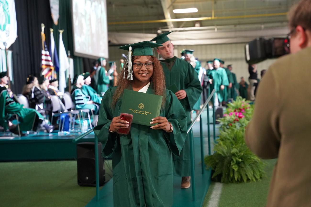 A graduate holds her diploma