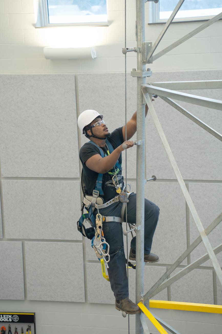A renewable energy student climbs a tower in the college's ACET Center