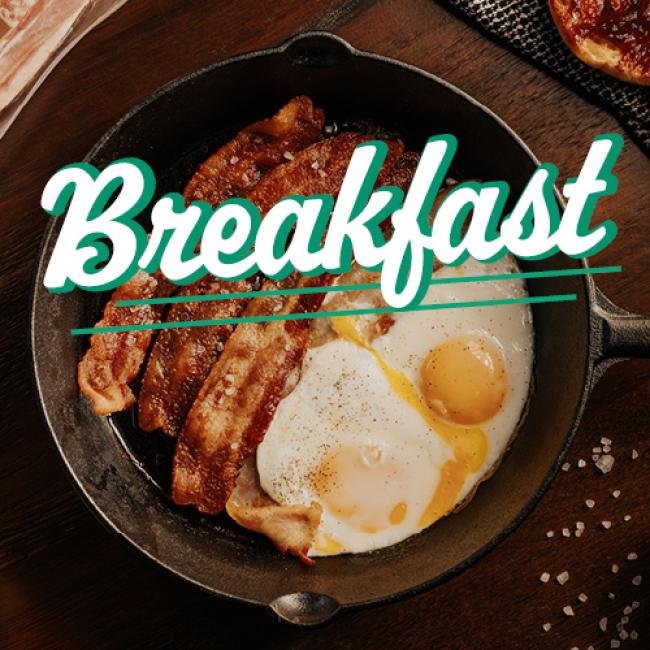 cast iron skillet with eggs and bacon cooking