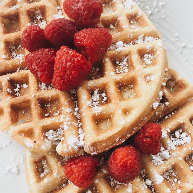 Two waffles with raspberries and powdered sugar